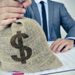Person holding burlap sack with dollar sign