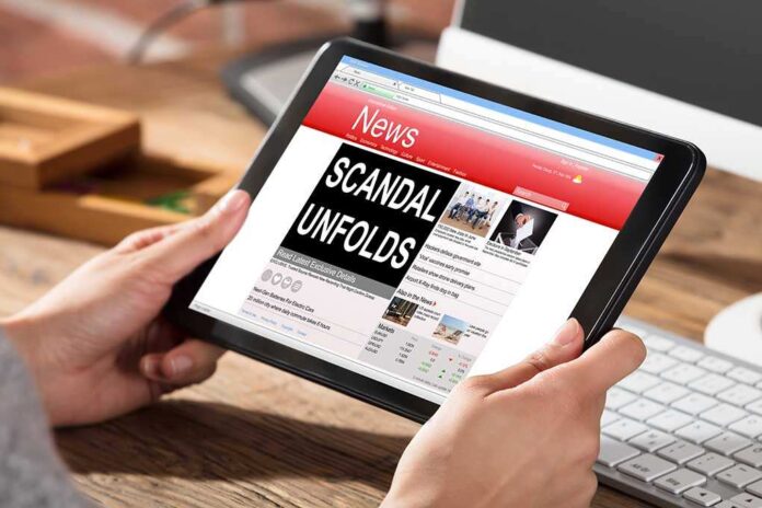 625950956 featured image Person holding tablet displaying news headline Scandal Unfolds.
