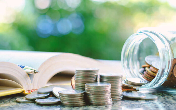 1037648761 featured image Open book pen coins jar on table