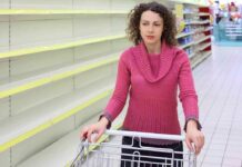 Woman in pink sweater with empty store shelves