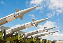 Multiple missiles pointed upward on launchers against blue sky