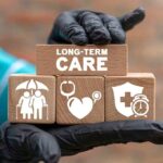 Gloved hand holding longterm care wooden blocks