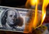 Hundred dollar bill burning with orange flames