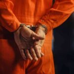 Person in orange jumpsuit with handcuffs behind back
