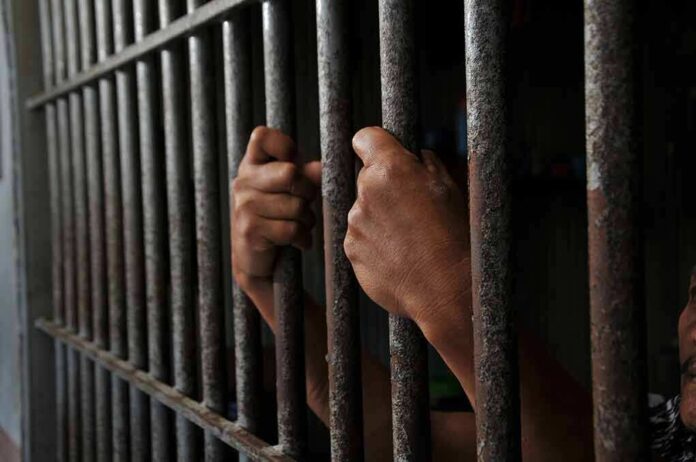 2452368639 featured image Hands gripping jail cell bars