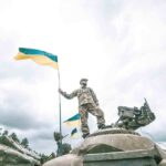Soldier on tank holding Ukrainian flag