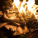 Stacks of hundred dollar bills burning in flames
