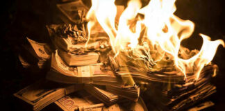 Stacks of hundred dollar bills burning in flames