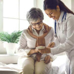 Doctor showing phone to a smiling elderly woman