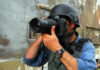 Person in helmet taking photos with a large camera