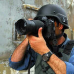 Person in helmet taking photos with a large camera