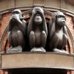 Three wise monkeys statue on a brick building