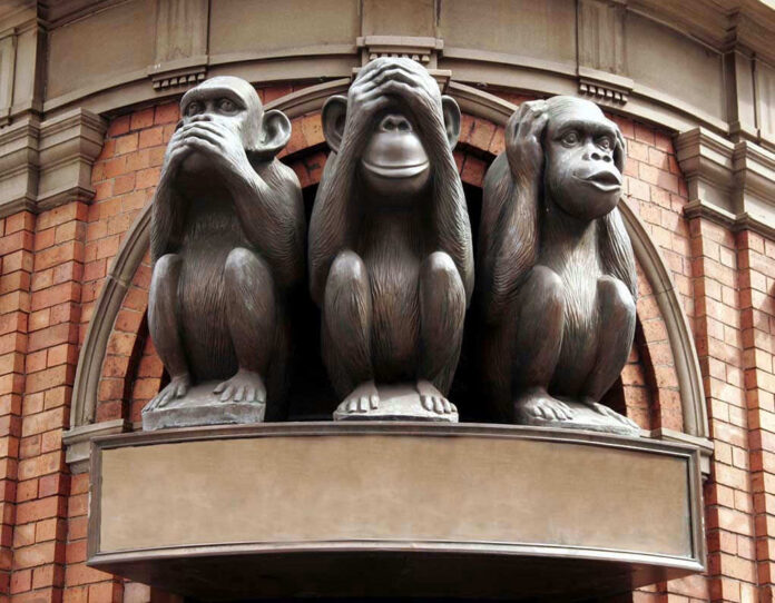 Three wise monkeys statue on a brick building