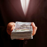 Hand holding a stack of hundred dollar bills