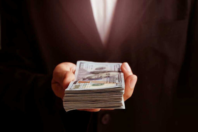 71912373 Hand holding a stack of hundred dollar bills