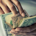 Person holding multiple US dollar bills