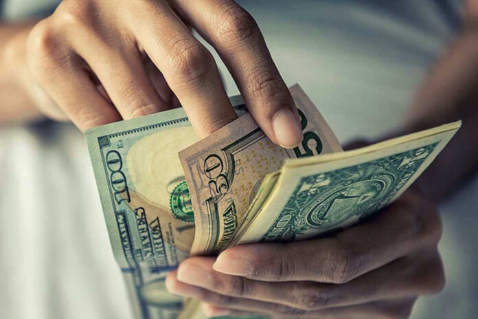Person holding multiple US dollar bills