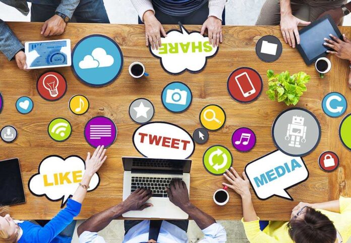 shutterstock_189811238.jpg Top view of a collaborative workspace with social media icons and people using laptops