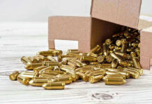 Box of brass bullets spilled on wooden surface