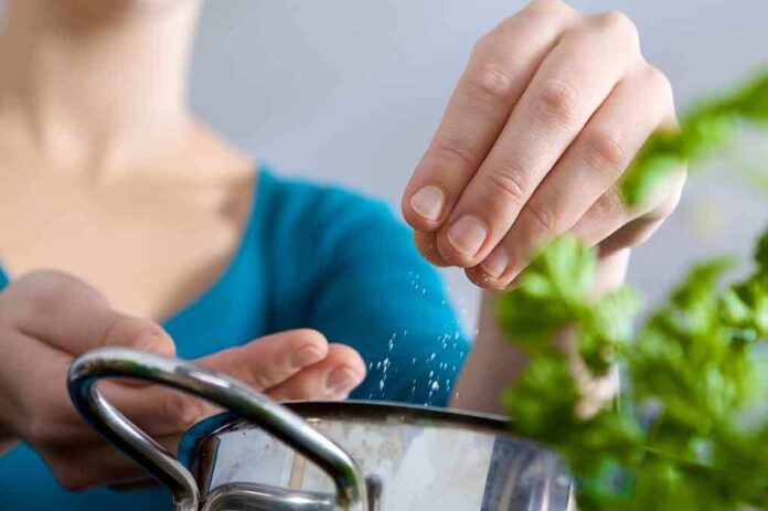 Person seasoning food with herbs from a pot