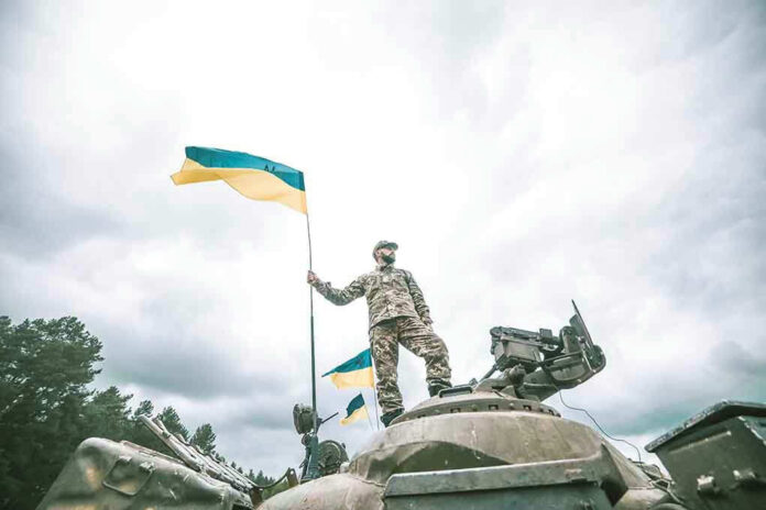 Soldier on tank holding Ukrainian flag