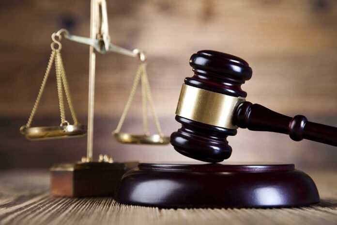 A wooden gavel and scales of justice on a wooden surface