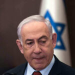 Netanyahu’s Legal Drama: Political Witch Hunt? Man in suit with Israeli flag in background