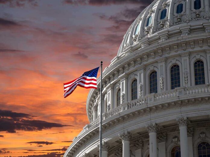 US Capitol building with an American flag against a sunset sky