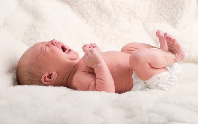 shutterstock_154248668.jpg A newborn baby lying on a soft blanket crying with a distressed expression