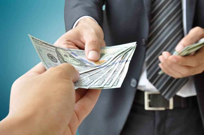 shutterstock_209123032.jpg Two hands exchanging cash in a business setting