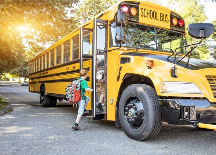 shutterstock_314871770.jpg A child with a backpack boarding a yellow school bus