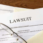 Pandemic Architect Claims POVERTY — Lawsuit For MILLIONS FILED Documents labeled Lawsuit with glasses on top.