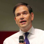Rubio’s War Plan: Venezuela in Crosshairs Man in white shirt speaking into a microphone