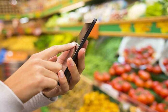 shutterstock_159877106.jpg Person using a smartphone while shopping for fresh produce in a grocery store