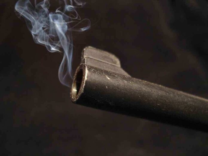 shutterstock_4250866.jpg Close-up of a gun barrel emitting smoke against a black background