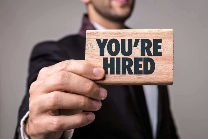 Person holding a Youre Hired sign.