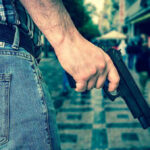 Armed, Naked Thief Baffles Florida Cops Person holding a gun in a crowded street.