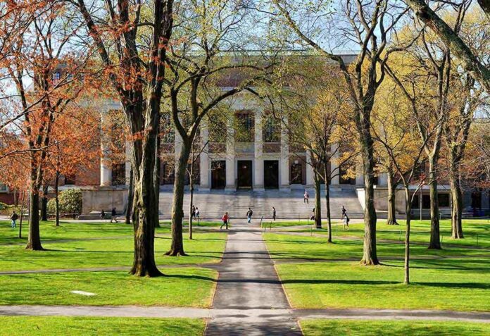 Students walking on a university campus with autumn trees and a historic building in the background