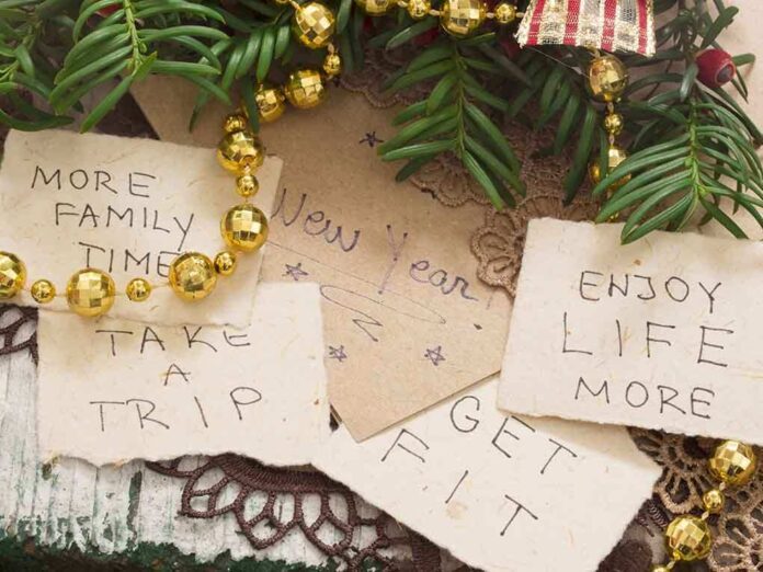Handwritten New Year resolutions on paper surrounded by holiday decorations