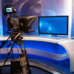 Reality TV Villain Targets Los Angeles Mayor’s Seat TV studio with camera and empty anchor desk.