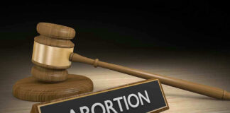 Gavel and sign reading Abortion on a wooden surface.