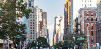 Busy city street with pedestrians, cars, and tall buildings.