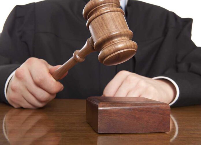 A judge holding a gavel above a wooden block