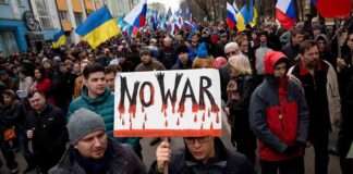 Crowd of protesters holding a sign that says NO WAR during a demonstration