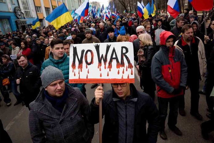 Crowd of protesters holding a sign that says NO WAR during a demonstration