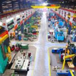 John Deere’s $70M American Revival: Tariff Triumph Aerial view of a large industrial workshop filled with various machinery and equipment