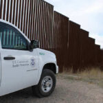 $70M ICE Warehouse Buy Stuns Arizona Border protection vehicle near a large metal fence.