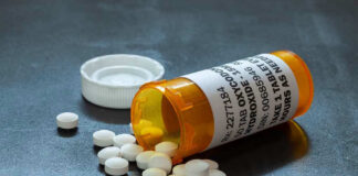 Open pill bottle with white tablets spilled out.