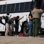 650 Arrests in West Virginia’s ICE Raid Border patrol officers investigating people near a bus.