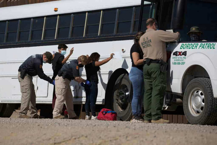 Border patrol officers investigating people near a bus.